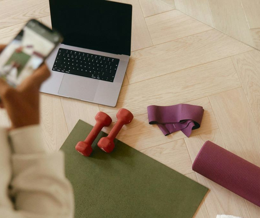 Woman on her phone with laptop lying on the floor in the background