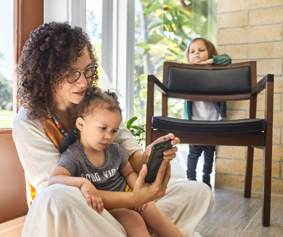 Woman sitting with child looking at phone