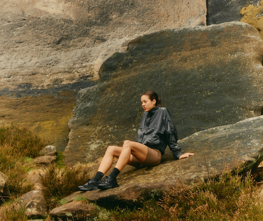 Woman in sports gear sitting on a rock in nature
