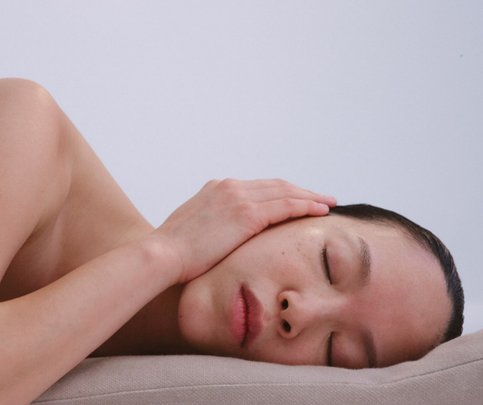 Woman lying in bed with hand on ear