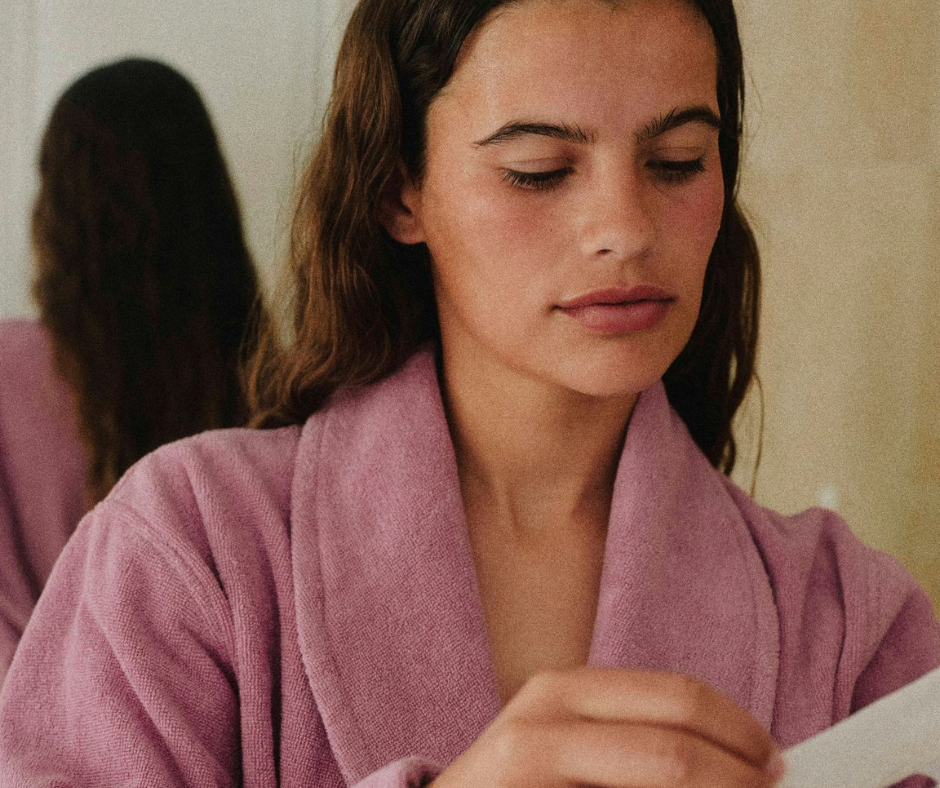 Woman in pink bathrobe reading paper in hand
