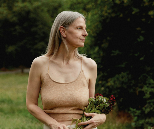 A middle aged woman standing in a garden with flowers in her hand