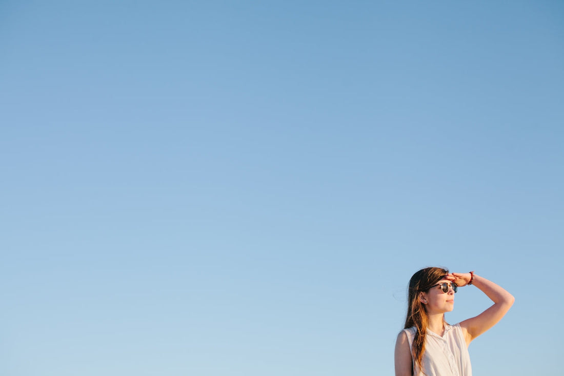 Lady in sunglasses looking out to the distance in front of a bright blue sky