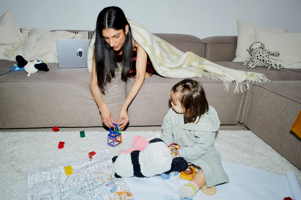 Woman and child playing with toys on the floor in a living room. 